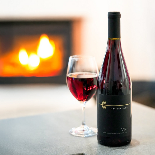 MW Gamay on a concrete bar with a glass poured next to in. A fireplace is faded out in the background